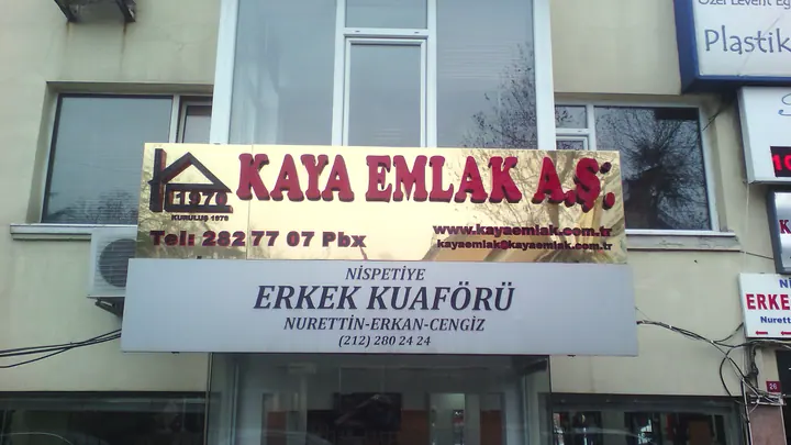 Kaya Emlak cephe tabelası — Yansıtıcı zemin ve marka yazılı cephe tabelasının görünümü.